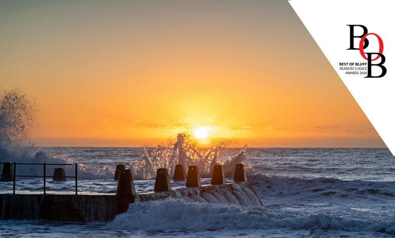 Sunset with waves crashing over a rock pool
